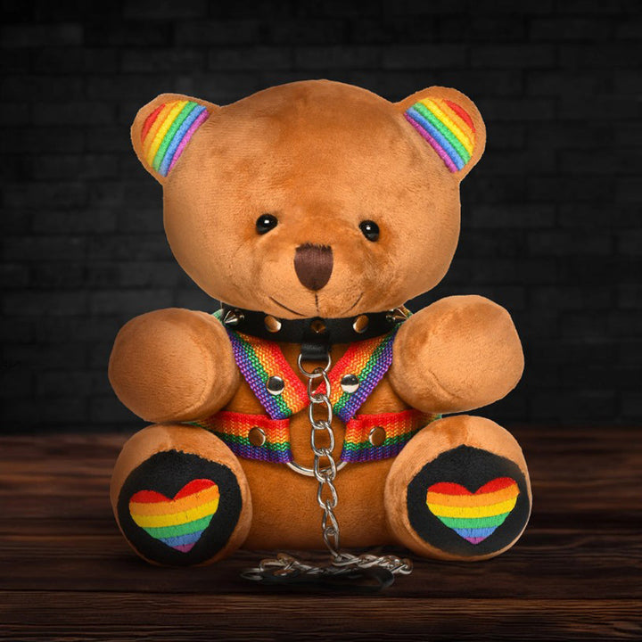 XR Pride Teddy Bear Plush with Rainbow Harness – tan plush bear with rainbow ears, feet and harness and a black spiked collar