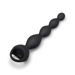 Angled view of black vibing beads showing magnetic charging contacts inside the finger-loop base