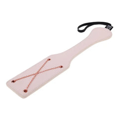 Angled view of blush pink faux-leather spanking paddle showing rose gold chain and wrist loop