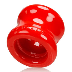 Angled bottom view of red Oxballs Squeeze stretcher revealing interior channel and ribbed grip