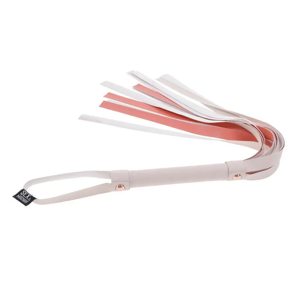 Angled view of Sex & Mischief flogger displaying branded tag, rose-gold hardware, and wrist loop