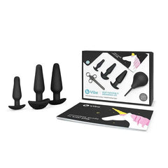 b-Vibe Anal Training Set with three black silicone plugs, anal bulb, dilator, and guide book beside retail box