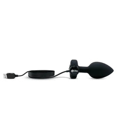b-Vibe plug lying flat with USB charging cable attached to base power port