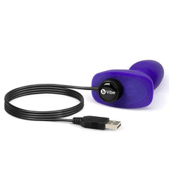b-Vibe Rimming Petite Plug connected to magnetic USB charging cable on white background