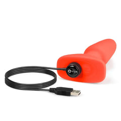 b-Vibe Rimming Plug 2 in orange silicone connected to magnetic USB charging cable