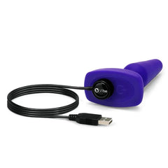 b-Vibe Trio Plug lying flat connected to magnetic USB charging cable, purple silicone