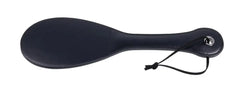 Back face of solid black paddle with stitched edges, metal eyelet, and black wrist cord