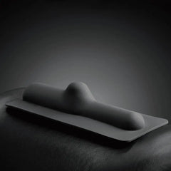 Bareback smooth silicone attachment resting on a dark leather surface, showing contoured shape