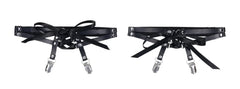 Close-up of black faux-leather laced garter straps with silver rivets and satin ribbon ties