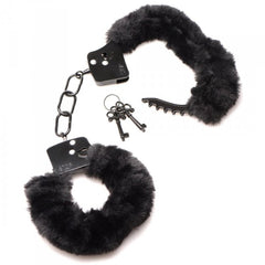 Black furry handcuffs laid flat with two matching black keys on a ring beside them