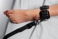 Black leather ankle cuff with locking buckle fastened around a wrist, strap attached