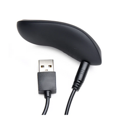 Black oval wireless remote control with USB charging cable attached showing underside detail