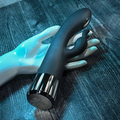 Black rabbit vibrator resting on a display hand, showing chrome ridged base detail