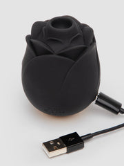 Black rose clitoral stimulator with USB magnetic charging cable attached, showing suction opening