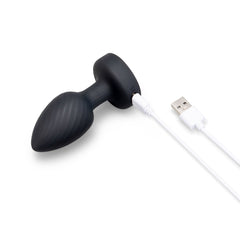Black silicone butt plug connected to white USB magnetic charging cable