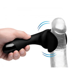 Black silicone penis teaser wand held by hand, showing vibrating sleeve fitting around a shaft