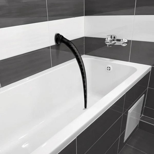 Black silicone tapered hose with suction cup mounted vertically inside a modern white bathtub