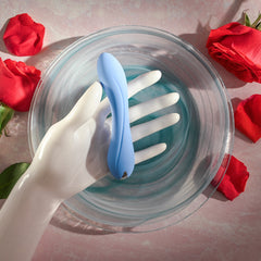 Blue Crush vibrator held by white ceramic hand in water bowl, surrounded by red roses