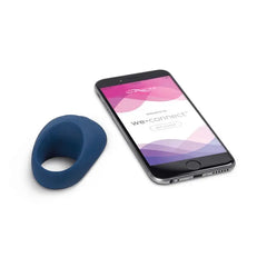 Blue We-Vibe Pivot ring beside smartphone displaying the We-Connect app for remote control