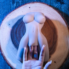 Body Language torso stroker resting on wood slice with hand shown for size scale reference from above