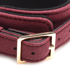 Close-up of burgundy suede cuff buckle with polished gold-tone hardware and black interior lining