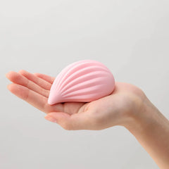 Compact pink shell-shaped Iroha Kushi vibrator resting in an open palm showing portable size