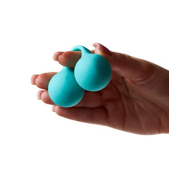 Compact teal dual-bulb vibrator resting in an open palm showing its small handheld size
