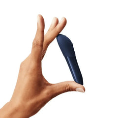 Compact We-Vibe Tango X bullet vibrator held between thumb and forefinger, showing small size