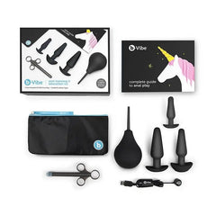 Complete b-Vibe Anal Education Set displayed flat including plugs, bulb, applicator, USB charger, bag, and guide