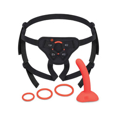 Complete b-Vibe strap-on set laid flat: black adjustable harness, red dildo, and three O-rings