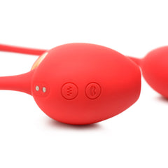 Control panel detail on red silicone egg showing two buttons and gold charging contact points