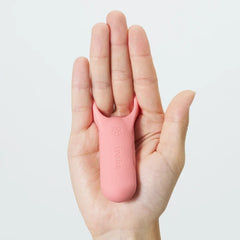Coral pink iroha paiRING+ resting in an open palm, illustrating its hand-sized scale