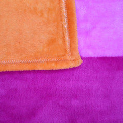 Corner detail of pride blanket showing orange and purple reverse side with stitched hem edge