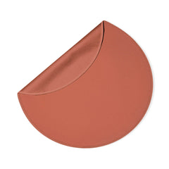Corner of round blanket folded back to reveal dual-layer construction in warm coral tone