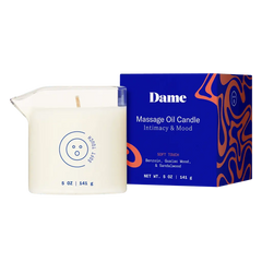 Dame Soft Touch Massage Oil Candle beside bold blue gift box listing Benzoin and Sandalwood