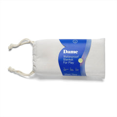 Dame Waterproof Blanket For Play in oat, rolled and stored in a natural drawstring bag