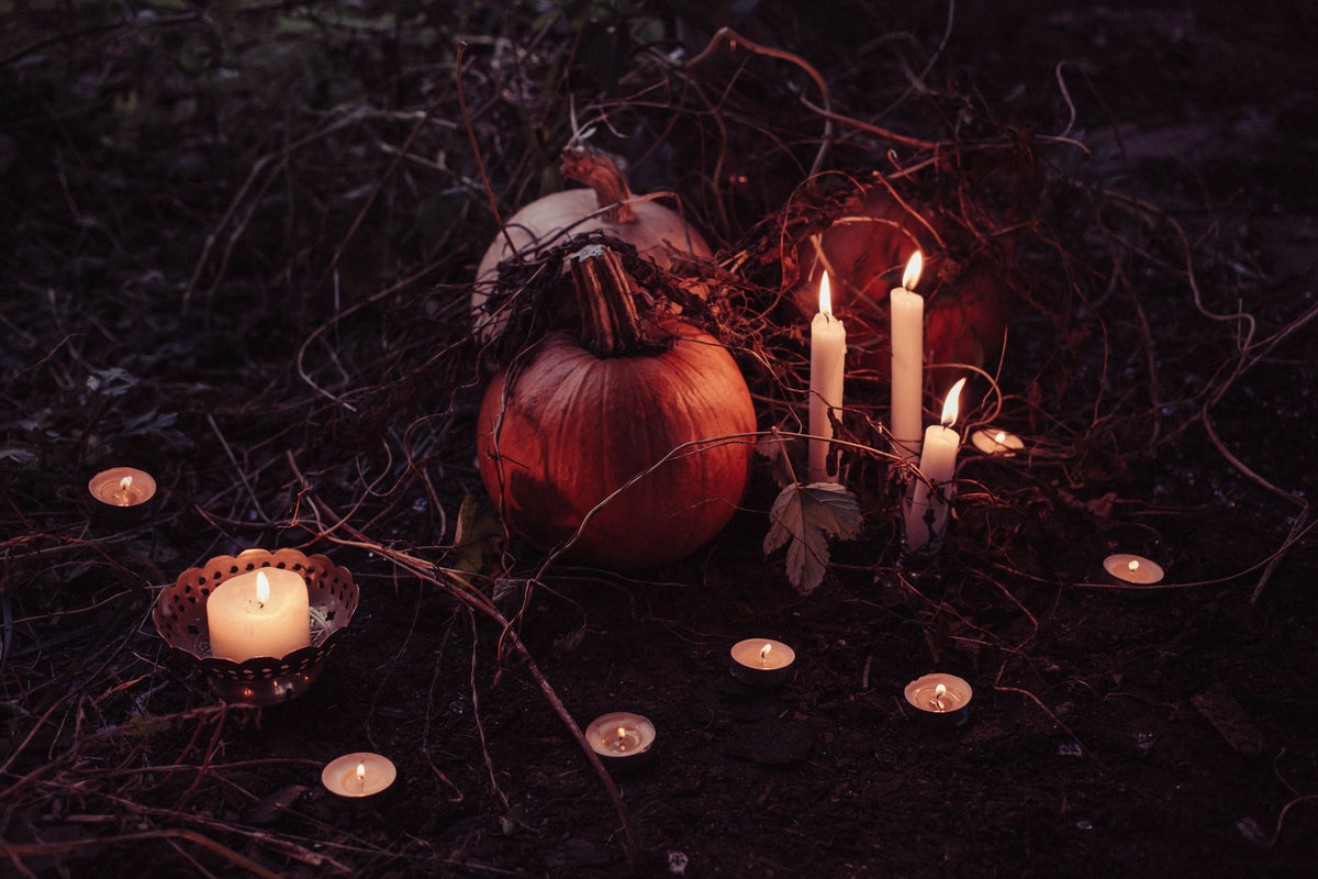 Carved jack-o'-lantern glowing beside lit candles in a dark room