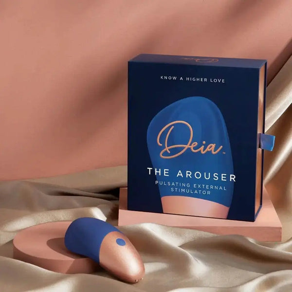 Deia The Arouser clitoral stimulator beside its navy and rose gold gift box