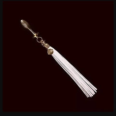 Detachable white flogger tail plug kit shown from reverse angle, highlighting gold ribbed plug handle and tassel cap detail