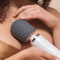 Dotted charcoal silicone texture cover fitted on a le Wand massager, pressed gently to shoulder