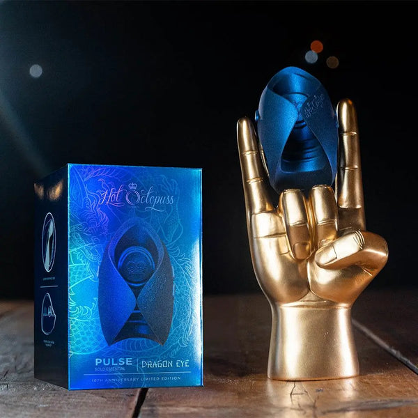 Dragon Eye masturbator held by gold display hand beside iridescent 10th anniversary edition box