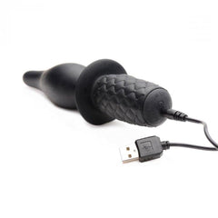 The Drop silicone thruster lying flat with USB charging cable connected to the base of the handle