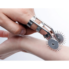 Close-up of dual spiked pinwheel wheels rolling across wrist skin, showing smooth rotating motion