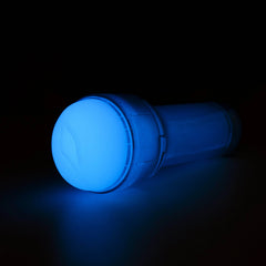 Feel Glow stroker lying at an angle glowing bright blue in dark setting, entry end facing forward