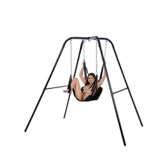Female model seated in Extreme Sling on black steel stand, arms raised holding suspension chains