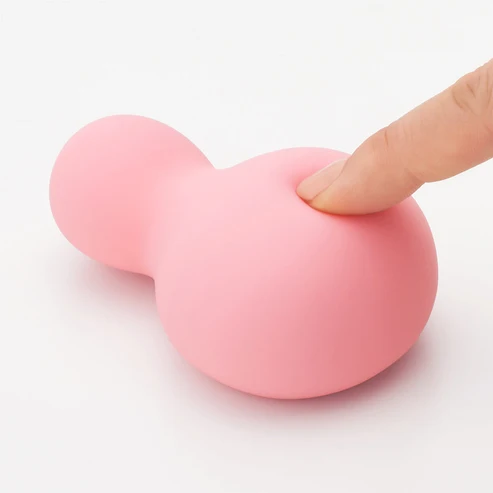Finger pressing control button on pink YUKI Nadeshiko vibrator to demonstrate soft silicone flex