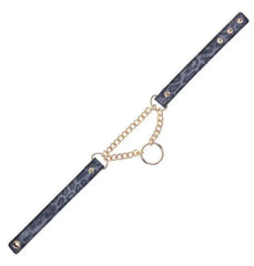 Flat lay of black collar strap with gold curb chain and circular ring hardware