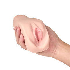 Flexible beige TPE stroker squeezed in one hand demonstrating ultra-soft, pliable material