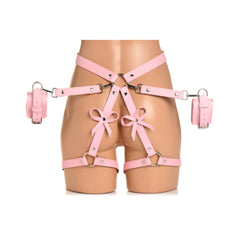Front mannequin view of pink bondage harness showing bow accents and attached wrist cuffs