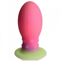 Front view of pink Xeno Egg silicone plug with gradient green suction base on white background